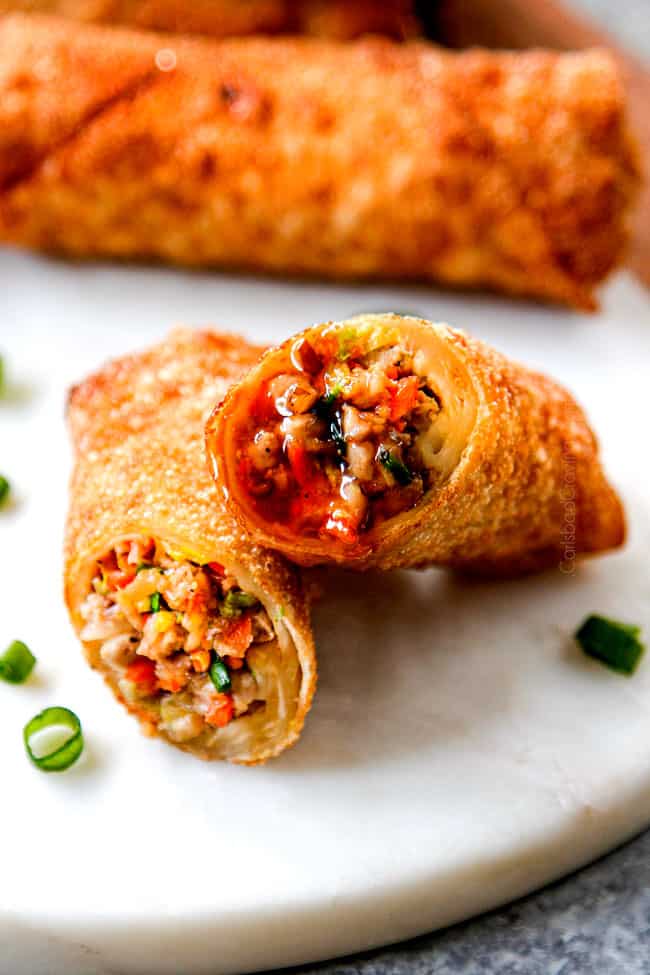 up close of two pork egg rolls dipped in dipping sauce