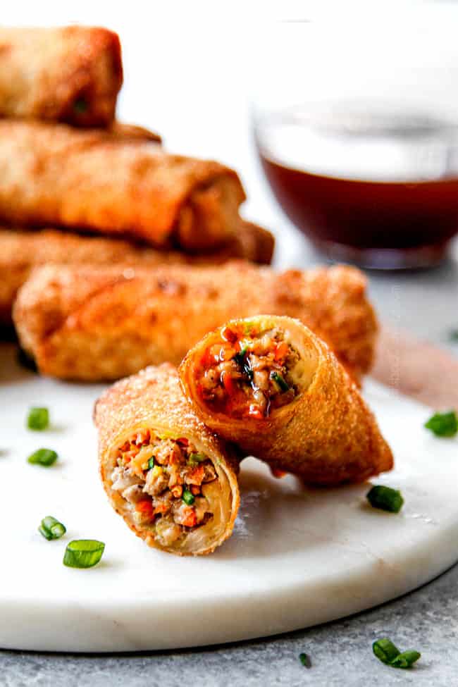 two homemade egg rolls stacked after being dipped in dipping sauce