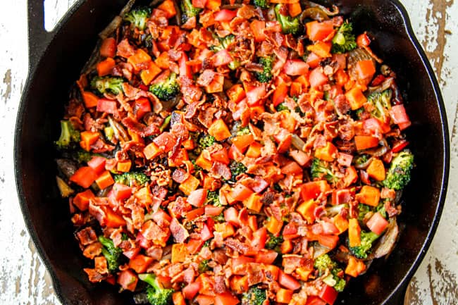 showing how to make egg frittata recipe evenly layering vegetables in a cast iron skillet followed by tomatoes and bacon