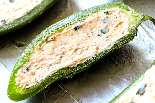 showing how to make jalapeno poppers by stuffing with cream cheese filling