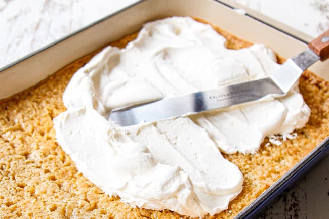 showing how to make best tres leches cake by frosting with whipped cream