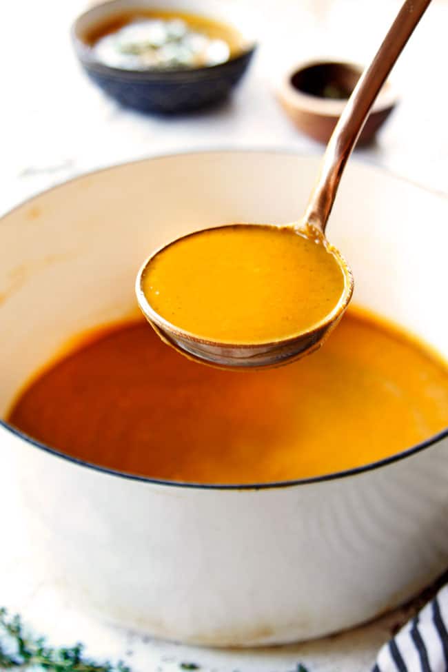 showing how to serve easy butternut squash soup by ladling the soup from a white pot