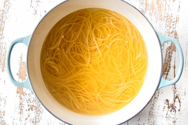 showing how to make Cacio e Pepe by boiling spaghetti or bucatini in a Dutch oven with little water