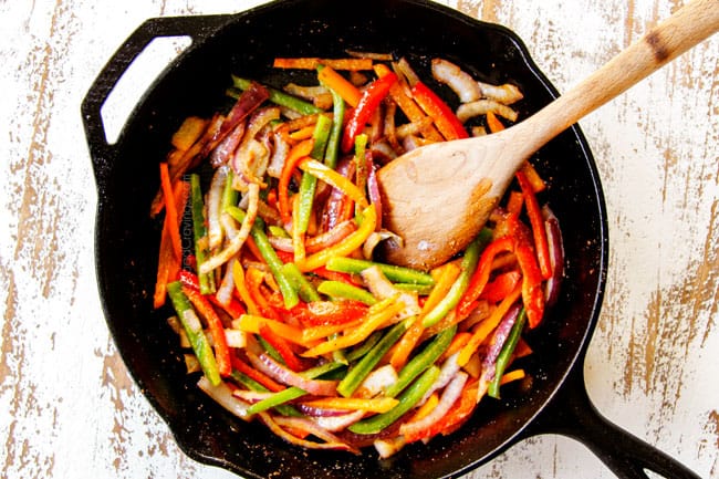 showing how to make Cajun shrimp pasta by cooking bell peppers and onions in a cast iron skillet
