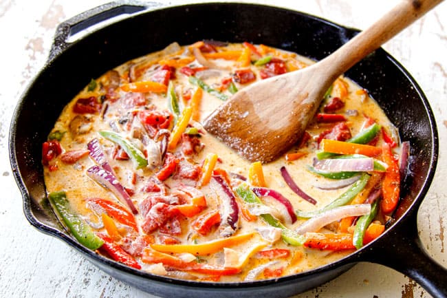 showing how to make Cajun shrimp pasta by adding chicken broth hand heavy cream to bell peppers