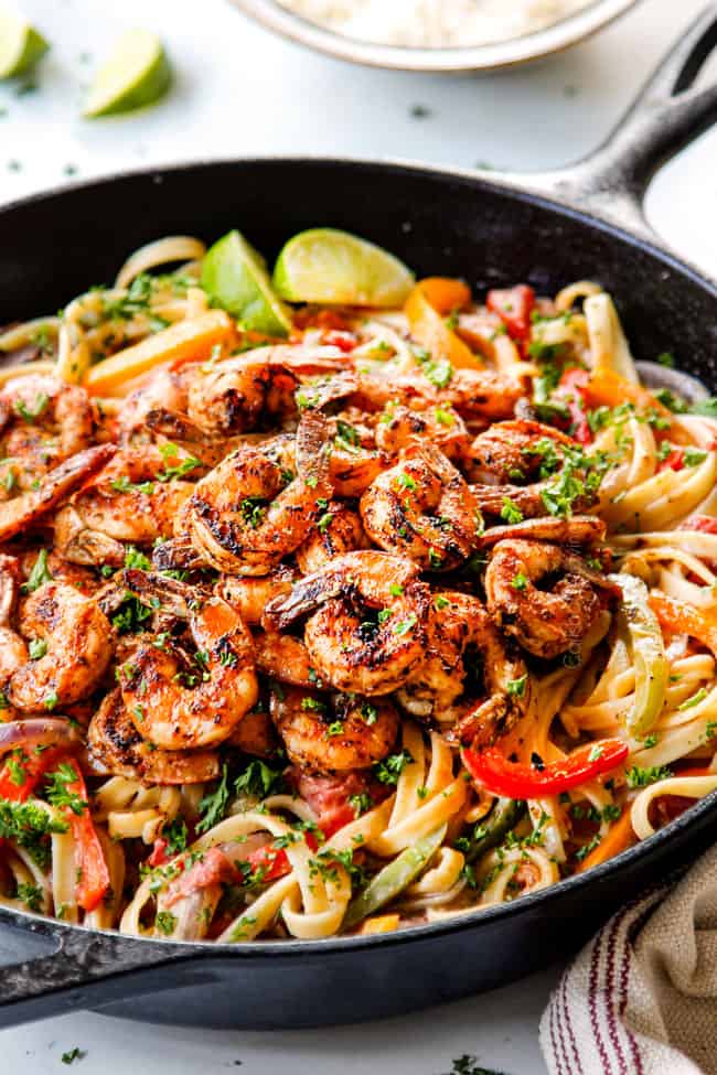 showing how to make creamy Cajun Shrimp Pasta recipe by adding blackened shrimp to pasta