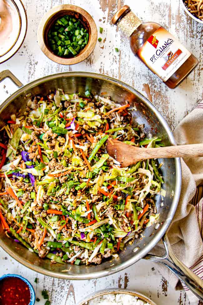 showing how to make egg roll in a bowl  garnishing with green onions and sesame seeds in a skillet