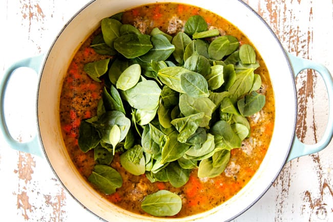 showing how to make Italian Meatball Soup by adding spinach to the soup