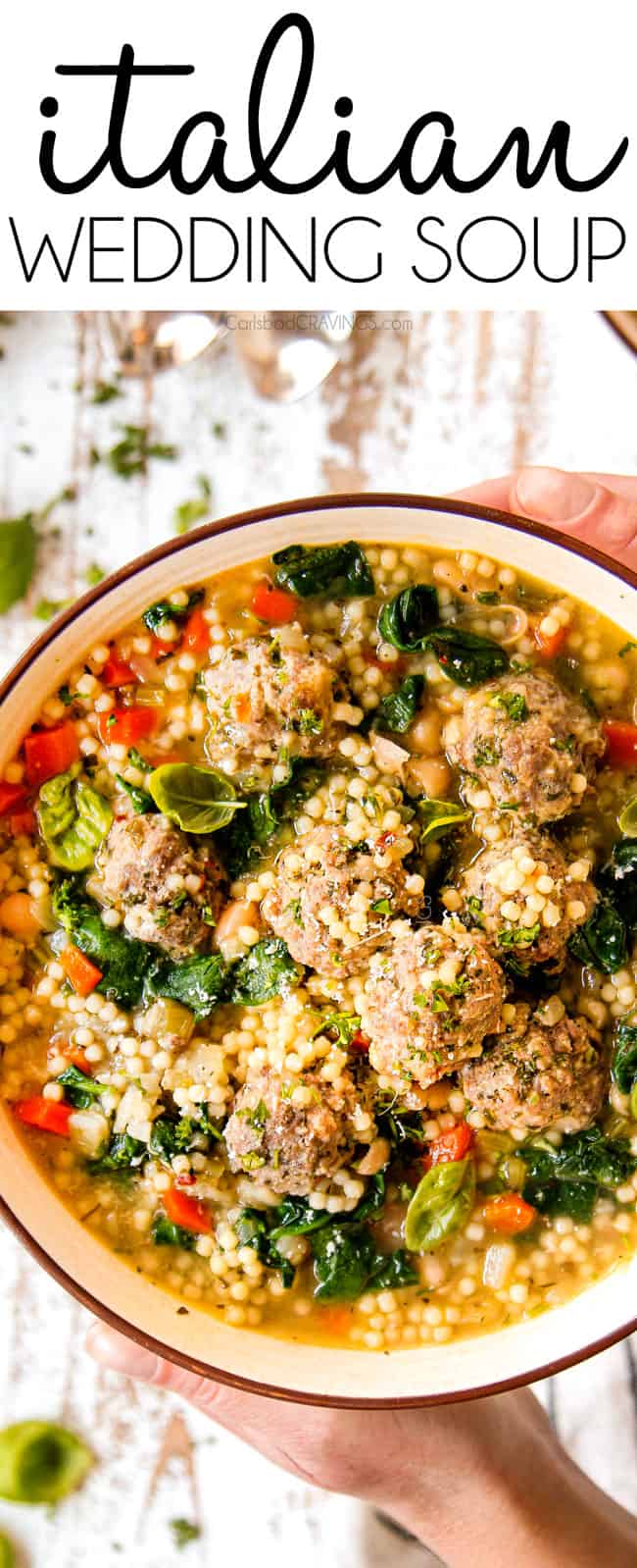 top view of two hands holding a bowl of authentic Italian Meatball Soup recipe