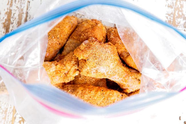 showing how to make lemon pepper wings by tossing chicken wings with lemon pepper seasoning