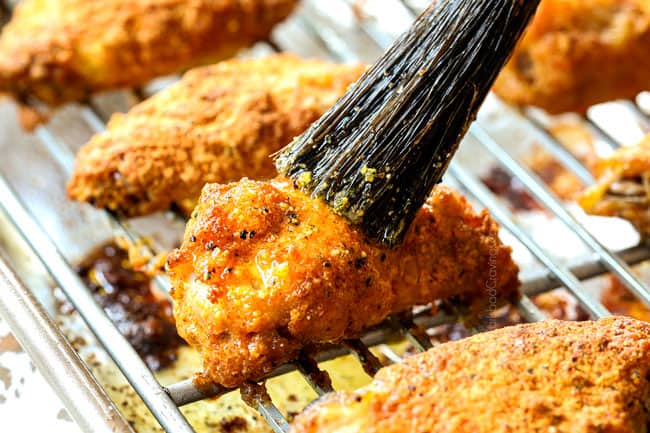 showing how to make baked lemon pepper wings by brushing wings with lemon pepper wings sauce