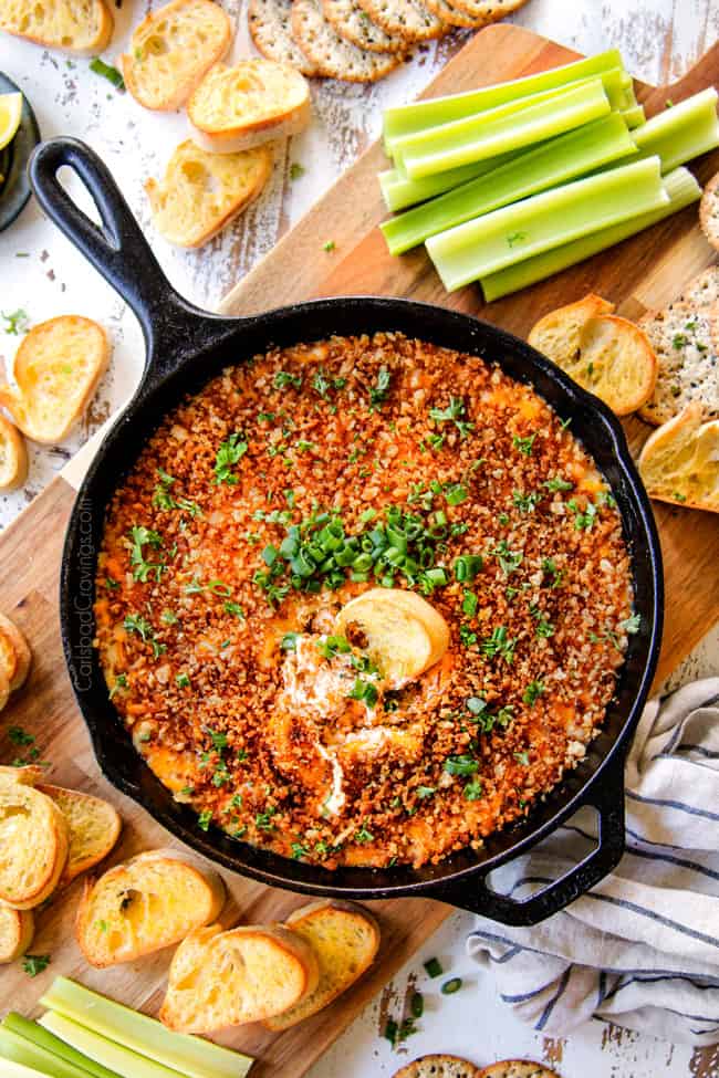 top view of showing what to serve with easy crab dip surrounded by vegetables, crackers, chips and baguette slices