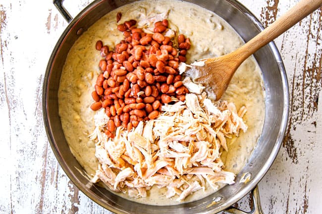 showing how to make green chicken enchilada casserole by stirring beans and chicken into enchilada sauce