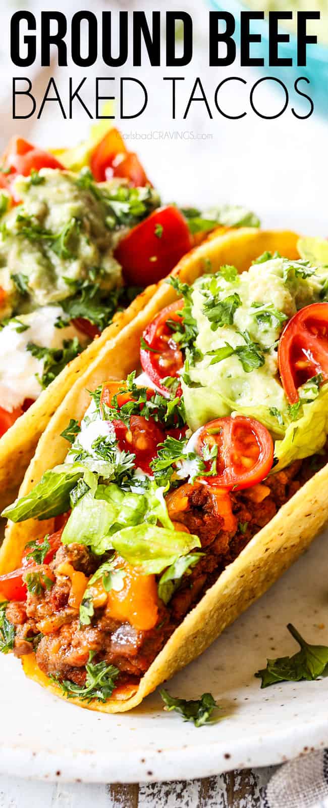 up close showing how to serve ground beef tacos by topping with lettuce, sour cream and tomatoes