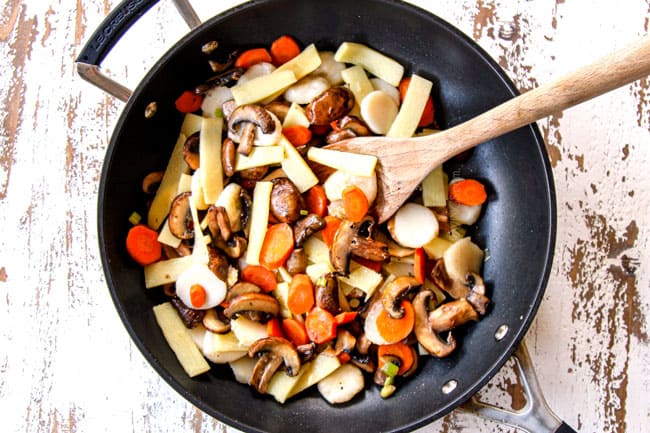 showing how to make Moo Goo Gai Pan by stir frying water chestnuts, bamboo shoots, garlic, ginger and green onions