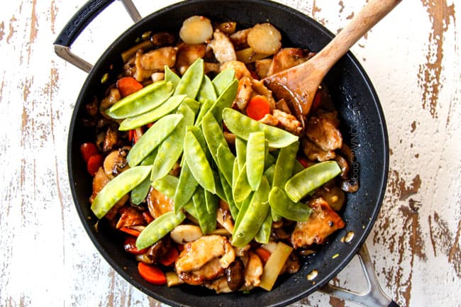 showing how to make Moo Goo Gai Pan by adding snow peas to the sauce and simmering for one minute