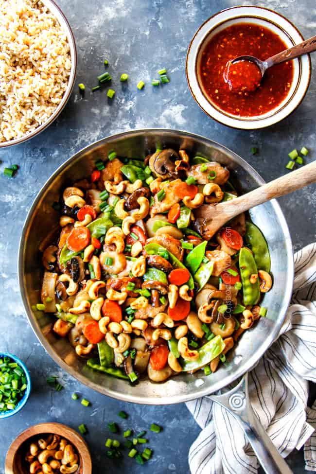 showing how to make Moo Goo Gai Pan by garnishing with green onions, cashews and chili sauce