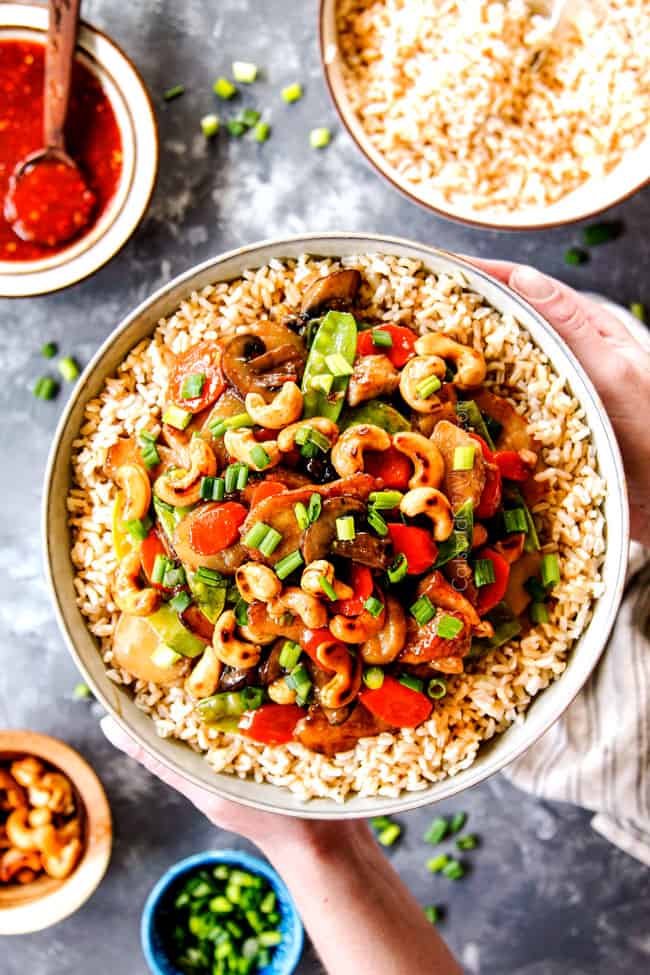 showing how to serve Moo Goo Gai Pan by adding stir fry to rice in a bowl