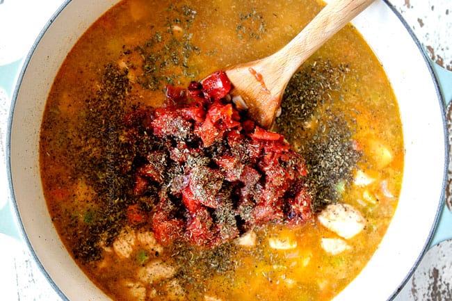 showing how to make creamy chicken and rice recipe by adding chicken broth, diced tomatoes and all seasonings to Dutch oven with chicken and rice