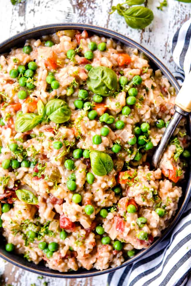 top view of a serving bowl of creamy chicken and rice garnished with parsley and peas, showing how to serve chicken and rice