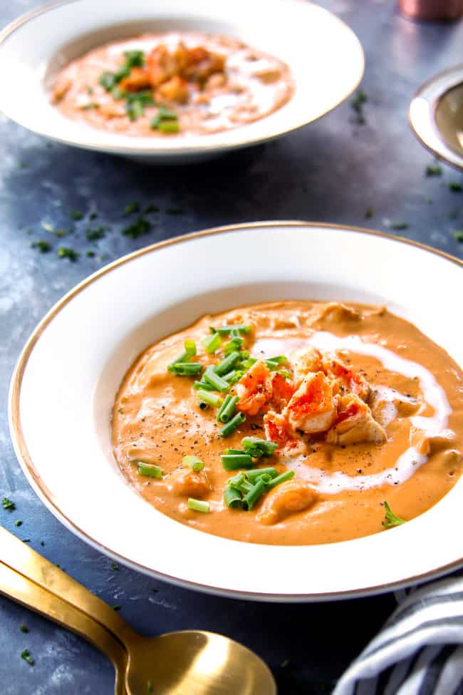 a bowl of lobster bisque soup garnished with heavy cream lobster and chives