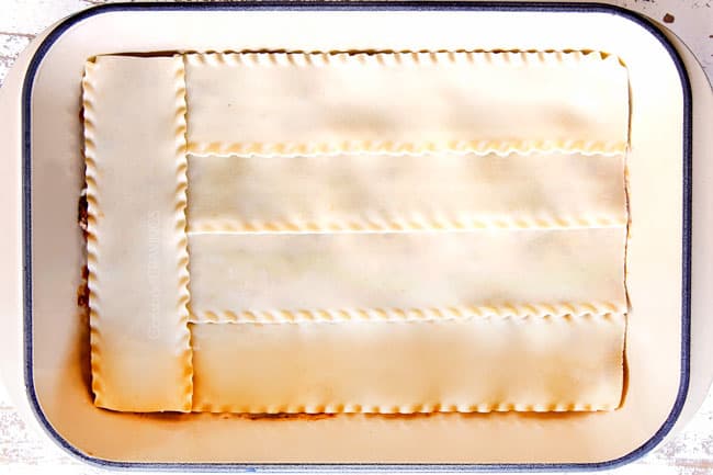 showing how to make Mexican Lasagna by layering meat sauce with lasagna noodles