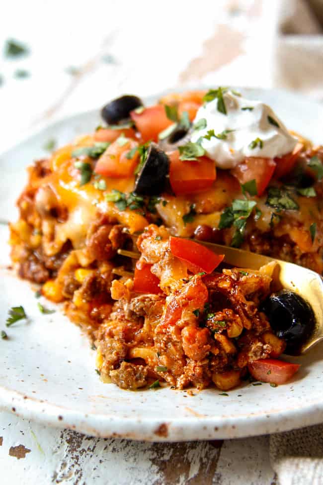 showing how saucy Mexican Lasagna recipe is by taking a bite with a fork