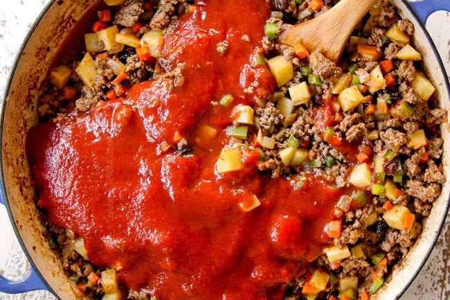 showing how to make Picadillo Mexicano by adding tomato sauce and beef broth to pot