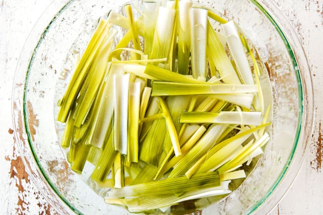showing how to make potato leek soup by washing leeks in a bowl of water
