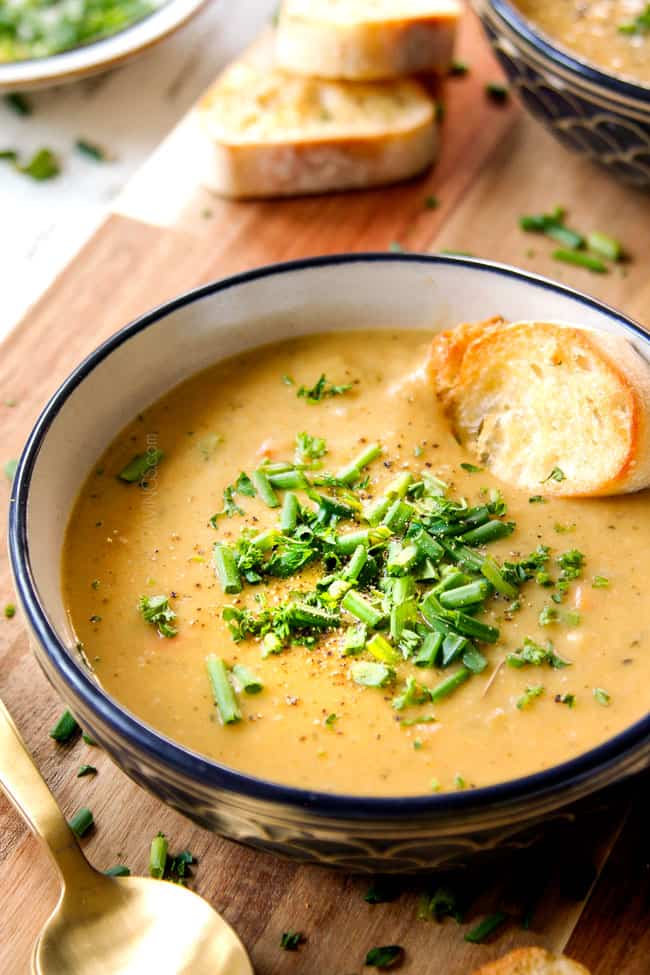showing how to season Leek and Potato Soup recipe by adding freshly cracked salt and pepper and a splash of lemon juice