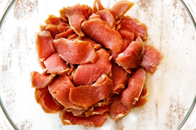 showing how to make ramen by marinating thinly sliced pork in a glass bowl