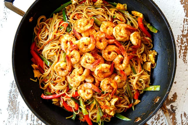 showing how to make Singapore Noodles by adding the cooked shrimp back to the skillet along with the eggs and tossing to combine