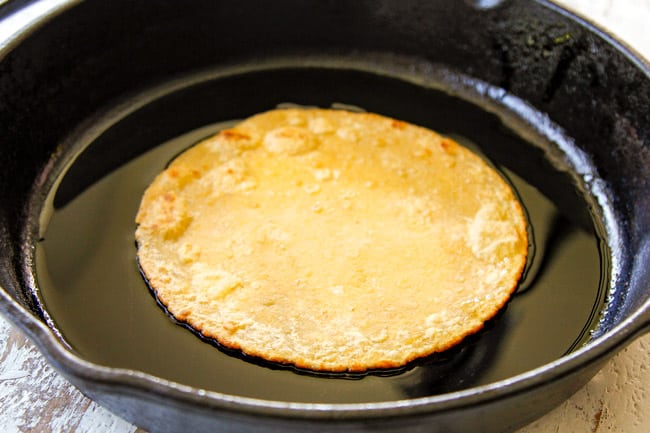 showing how to make easy chicken enchiladas by flash frying corn tortillas in a cast iron skillet