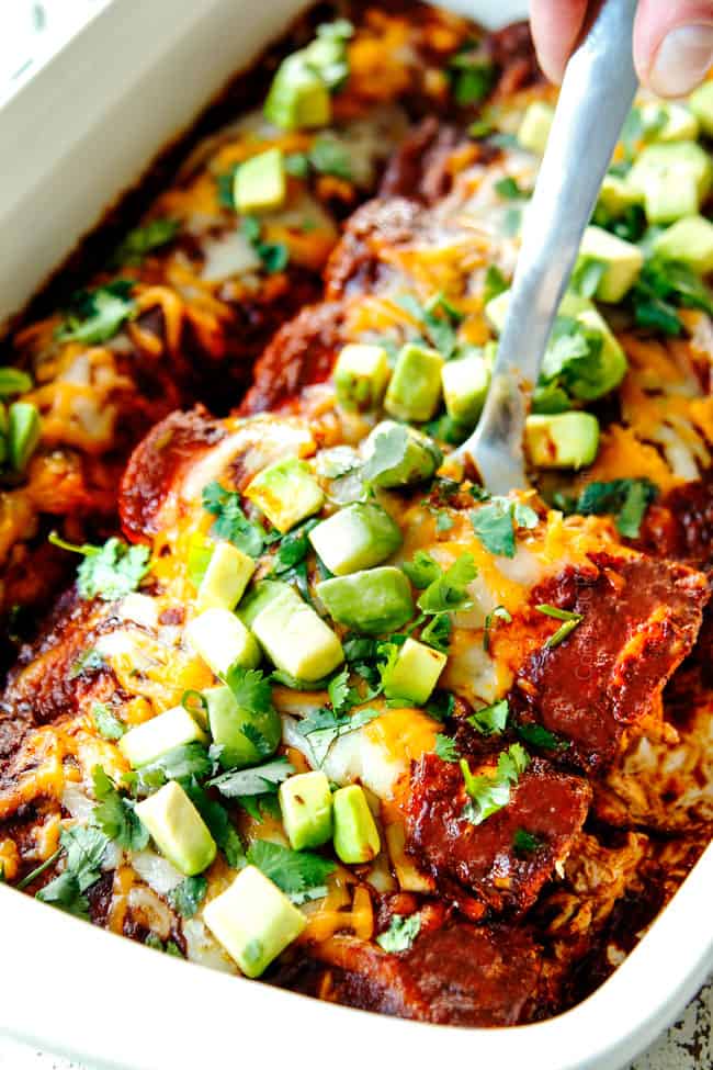 showing how to serve easy chicken enchiladas by scooping up two enchiladas with a metal spatula