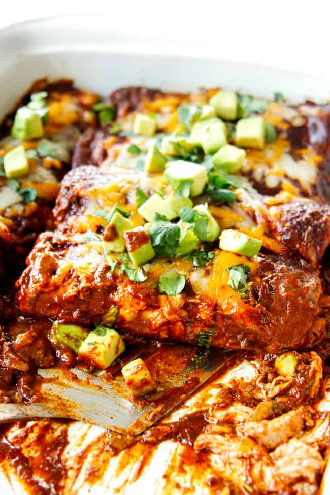 serving easy chicken enchiladas with a metal spatula and a half eaten baking dish