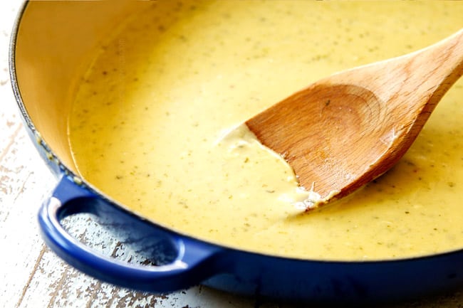 showing how to make salmon pasta by simmering heavy heavy cream, pesto and Parmesan until creamy