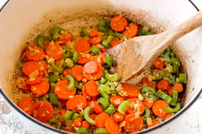 showing how to make Cabbage Soup by sauteeing onions, carrots and celery in a Dutch oven