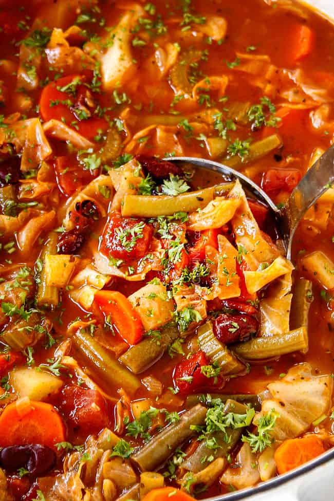 showing how to serve Vegetable soup with Cabbage by scooping up a big spoonful of soup