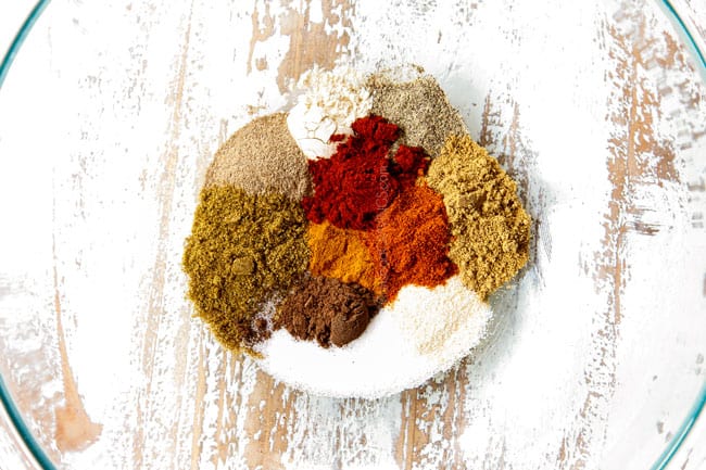 showing to make chicken shawarma into bowls by adding cumin, coriander, paprika, turmeric, cayenne, onion powder, garlic powder, salt and pepper to a bowl