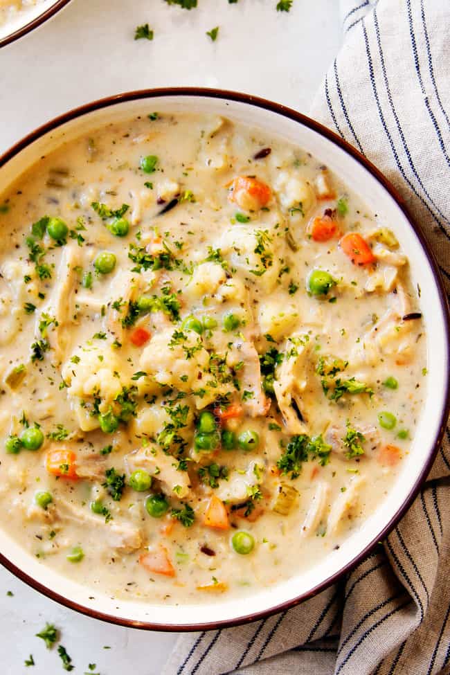 top view of a bowl of creamy chicken and wild rice soup with chicken, carrots, celery, peas and cauliflower