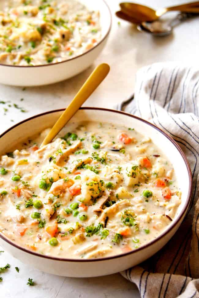 two bowls showing how to serve chicken and rice soup by adding parsley, salt and pepper