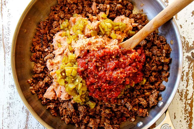 showing how to make tostada recipe by adding refried beans, salsa, and green chilies to ground beef