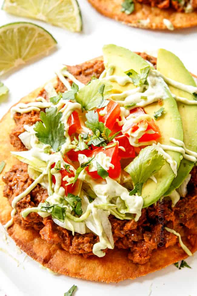 up close of tostada topped with beef, beans, lettuce and tomatoes to show how crisp the tostada shell is