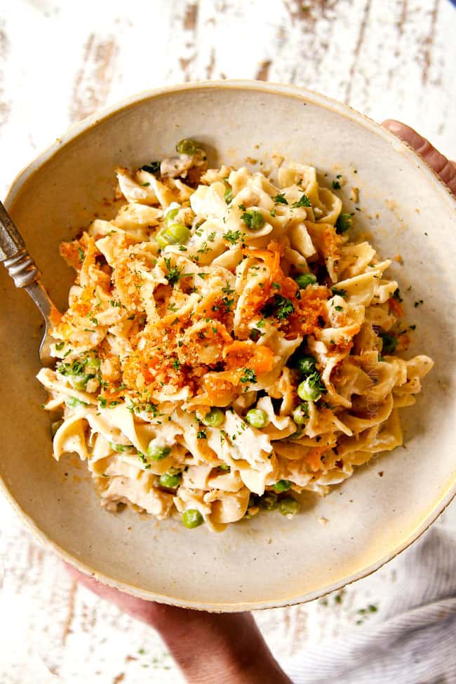showing how to serve Tuna Casserole recipe by adding to a plate and garnishing with parsley