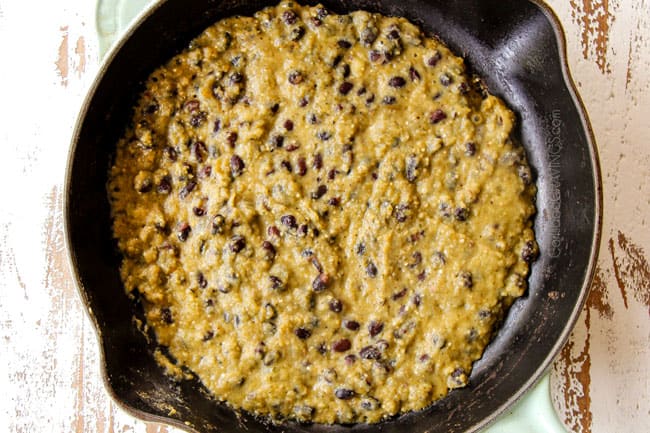 showing how to make Chilaquiles Verdes by adding salsa verde to a cast iron skillet and simmering