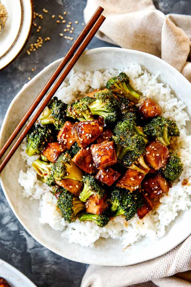 top view of a bowl of Chicken and Broccoli recipe over rice in a white bowl garnished with sesame seeds