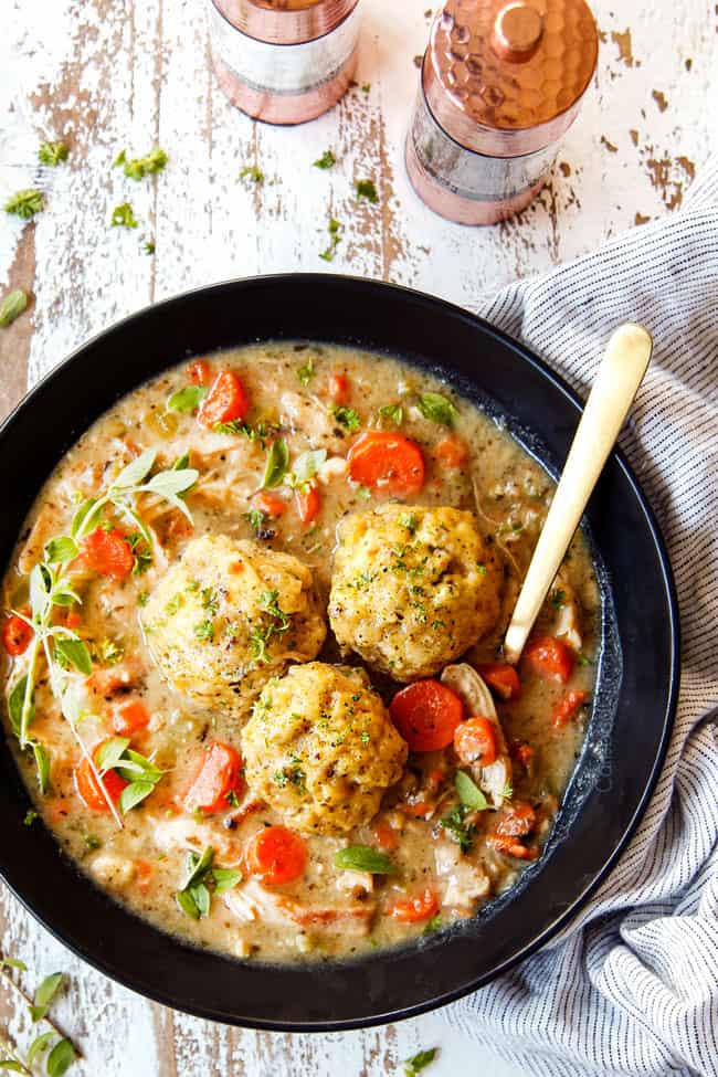 showing how to serve old fashioned chicken and dumplings recipe by adding three dumplings to a bowl of soup and garnishing with parsley