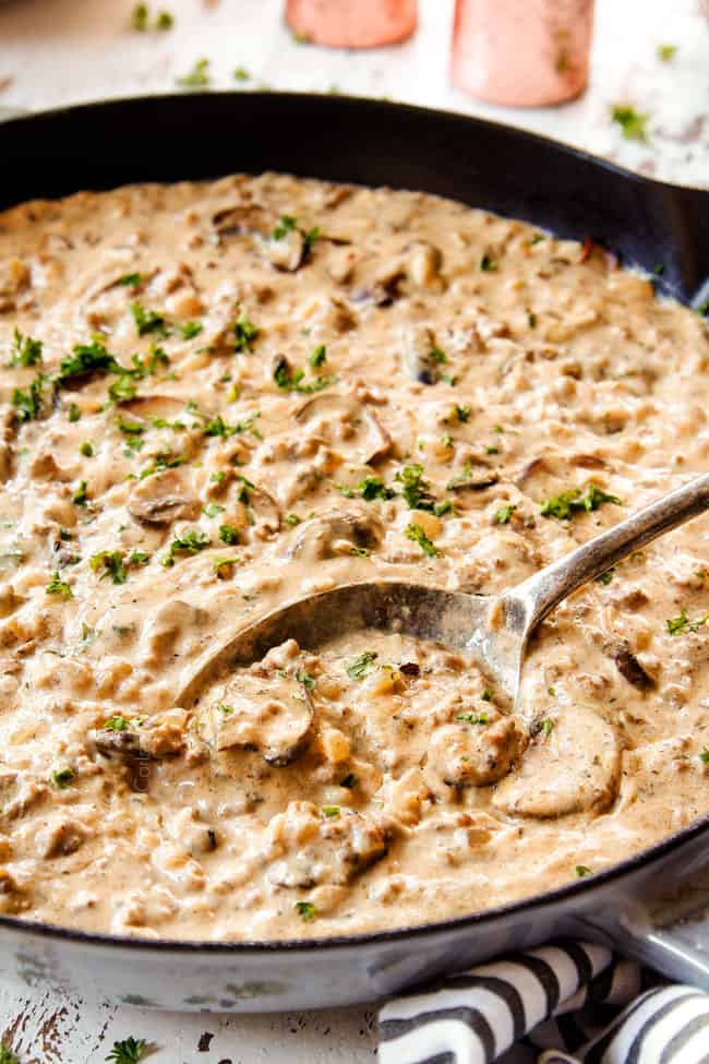 side view of a spoon in the ground beef stroganoff mushroom gravy showing how creamy it is