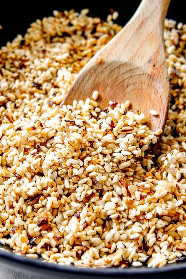 showing how to make mushroom risotto recipe by toasting rice with shallots in a black Dutch oven