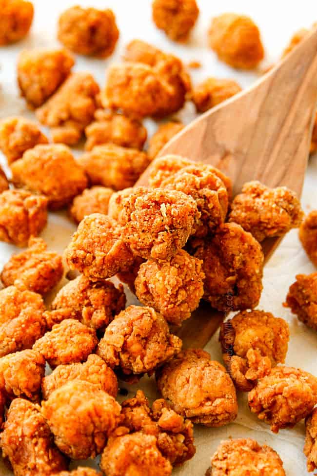 showing how to make KFC Popcorn Chicken recipe by scooping up chicken from draining on paper towels
